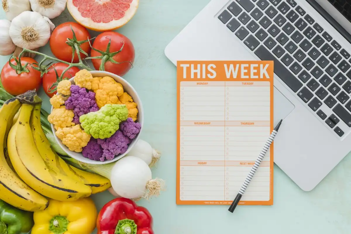 grocery list on a laptop next to vegetables